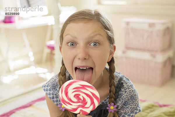 Mädchen lecken Lolli im Schlafzimmer