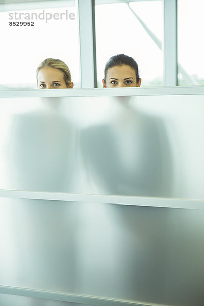 Geschäftsfrauen beim Blick über die halbe Wand im Büro