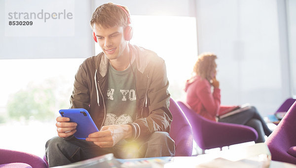 Universitätsstudent hört Kopfhörer in der Lounge