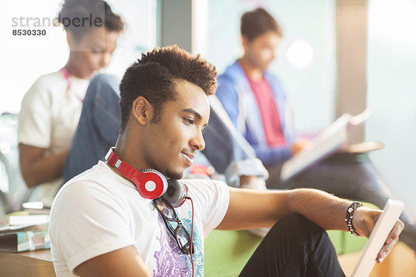 Universitätsstudent mit digitalem Tablett in der Lounge