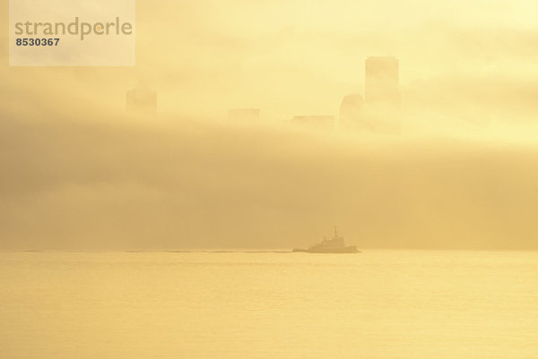 Silhouette von Schlepper und Nebel über der Skyline der Stadt