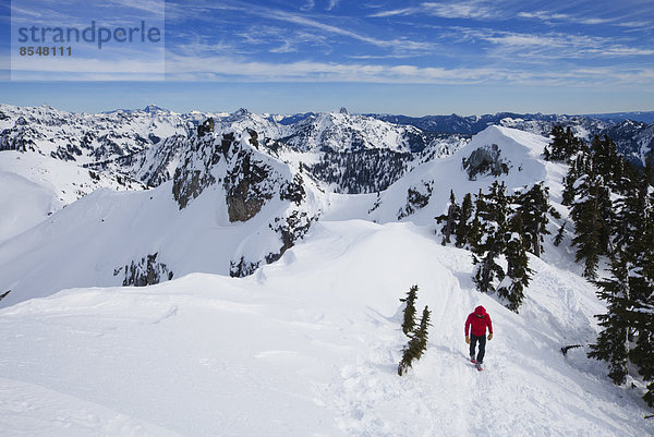 Ein Bergsteiger in einer roten Jacke auf dem Gipfel des Snoqualmie Peak im Cascades-Gebirge im Bundesstaat Washington  USA.