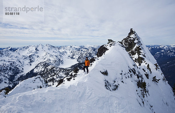 Ein Skifahrer auf einem Bergkamm  der vor dem Skifahren pausiert The Slot on Snoqualmie Peak in den Cascades Ranges  Bundesstaat Washington  USA.