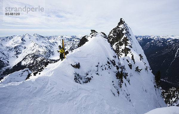 Ein Skifahrer steht auf einem Grat  bevor er auf dem Slot auf dem Snoqualmie Peak in der Cascades Range im Bundesstaat Washington  USA  Ski fährt.