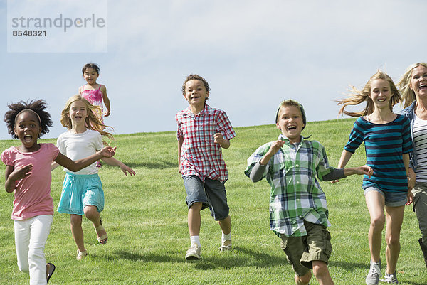 Eine Gruppe von Kindern rennt über einen Rasenplatz.