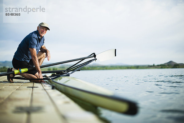 Ein Mann mittleren Alters auf einem Steg  der ein Ruderboot für einen Ausflug vorbereitet.