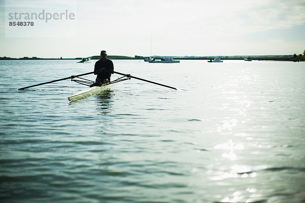 Ein Mann mittleren Alters in einem Ruderboot auf dem Wasser.