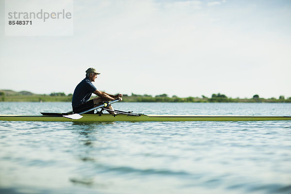 Ein Mann mittleren Alters in einem Ruderboot auf dem Wasser.