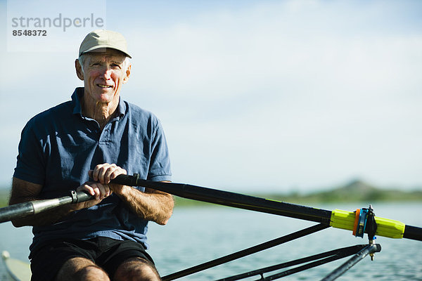 Ein Mann mittleren Alters rudert mit einem einzigen Totenkopf-Ruderboot auf dem Wasser.