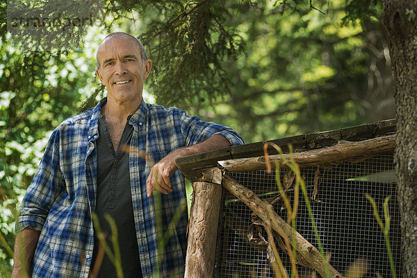 Ein traditioneller Biobauernhof in den USA und ein Mann  der sich an einen Zaun lehnt.