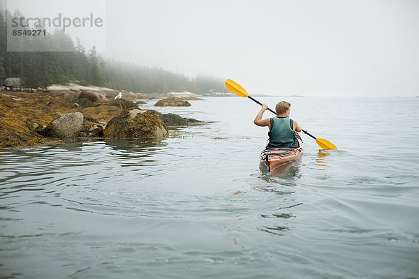 Ein Mann paddelt mit einem Kajak auf ruhigem Wasser bei Nebel. Bundesstaat New York  USA