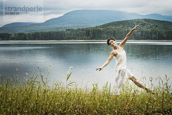 Eine Frau tanzt anmutig unter freiem Himmel entlang des Seeufers bei Woodstock  New York State  USA