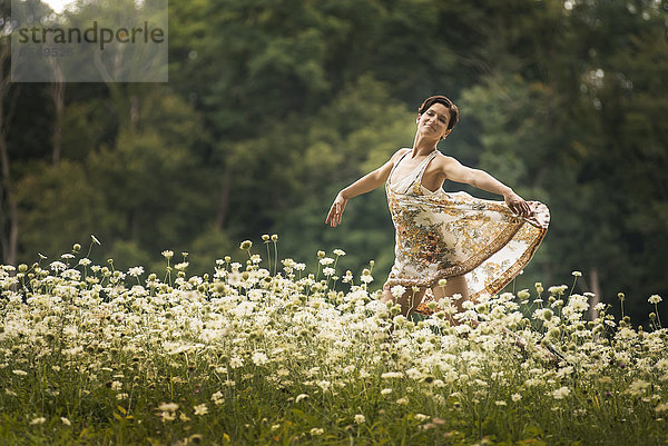 Eine Frau tanzt auf einem Feld mit Wildblumen.