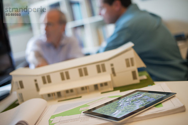 Architekten  die in einem Büro unter Einsatz von Computertechnologie an einem grünen Bauprojekt arbeiten. Das Modell eines Architekten für ein Haus. Computer-Tablett.