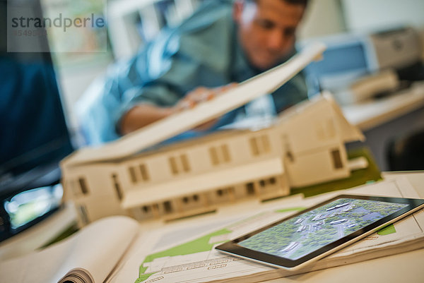 Architekten  die in einem Büro unter Einsatz von Computertechnologie an einem grünen Bauprojekt arbeiten. Das Modell eines Architekten für ein Haus. Computer-Tablett.