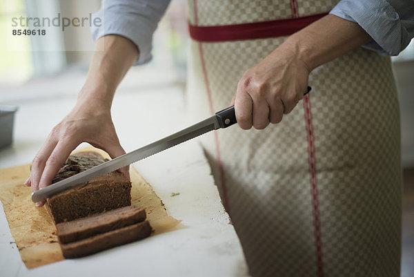 Eine Frau schneidet einen gebackenen Schokoladenkuchen an.