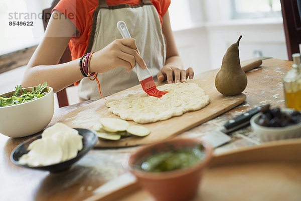 Eine Person  die einen Wrap mit frischen Zutaten und grüner Salsa macht.