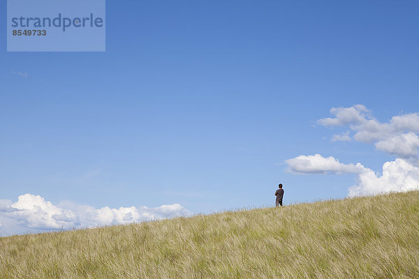 Ein Mann  der auf dem Kamm eines Hügels steht.