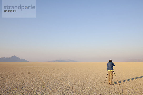 Mann mit Kamera und Stativ auf der flachen Salzpfanne oder Playa der Black Rock-Wüste  Nevada.