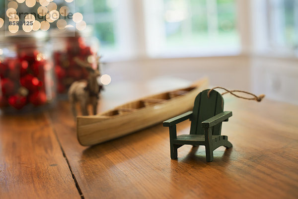 Weihnachtsdekorationen auf einem Tisch. Ein handgefertigtes Holzkanu und ein kleiner Stuhl.