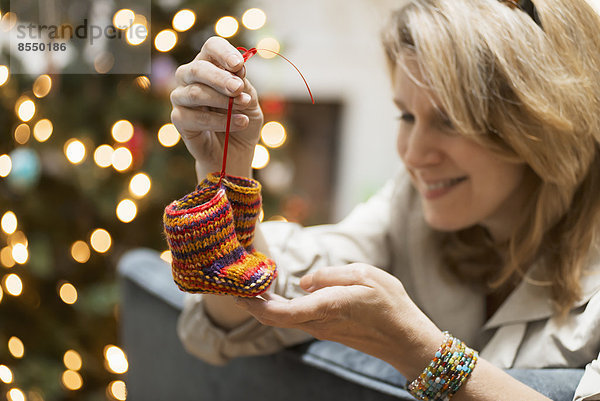 Eine junge Frau hält ein Paar handgestrickte Babyschuhe in der Hand.