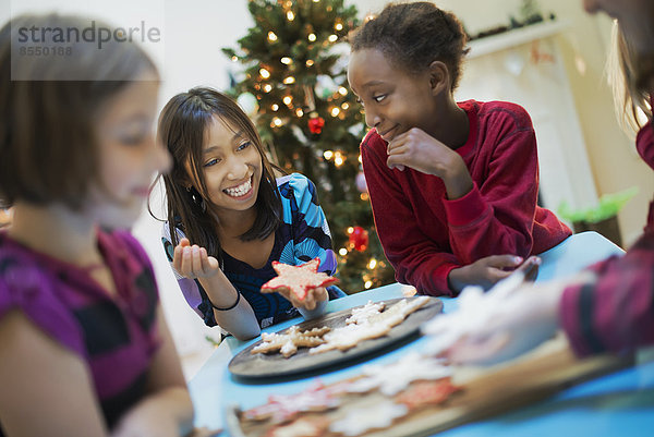 Eine Gruppe von Kindern um einen Tisch  die Bio-Weihnachtsplätzchen dekorieren.