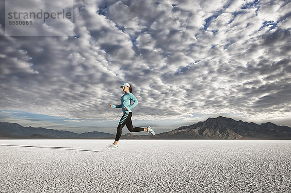 Eine junge Frau läuft durch die Landschaft auf der Salzfläche in der Nähe der Stadt Salt Lake City.