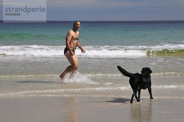 Mann Strand Großbritannien Badehose Hund Bucht spielen
