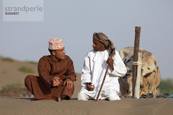 Omaner sitzen in traditioneller Kleidung im Gespräch  Barka  Al-Batina Provinz  Oman  Arabische Halbinsel