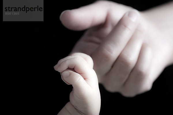 Baby umschließt mit seiner Hand den Finger seiner Mutter