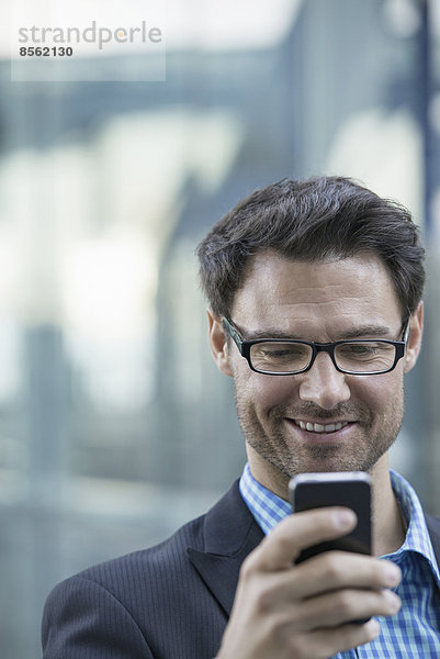 Geschäftsleute in der Stadt. Unterwegs in Kontakt bleiben. Ein Mann überprüft sein Mobiltelefon.