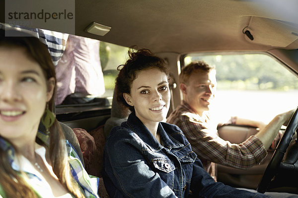 Drei Passagiere in der Kabine eines Pickup-Trucks. Ein junger Mann am Steuer. Zwei junge Frauen sitzen neben ihm.