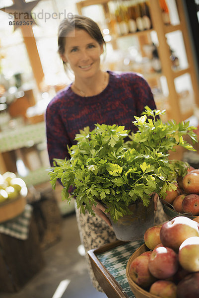 Biolandwirt bei der Arbeit. Eine Frau arbeitet an einem Bauernstand mit einer Ausstellung von frischen Produkten. Grüne Pflanzen und Schalen mit Äpfeln.