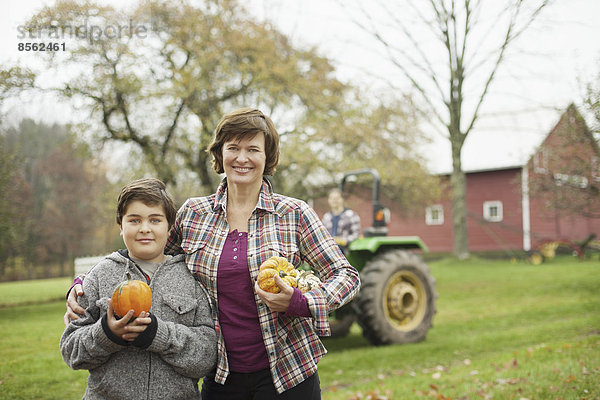 Zwei Personen  eine Frau und ein Kind auf einem Biohof  mit geerntetem Gemüse  Kürbissen und Kürbissen. Biologische Landwirtschaft.