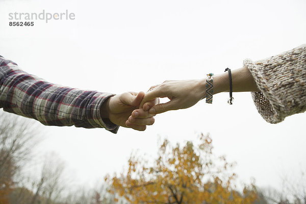 Zwei Personen halten sich an den Händen  ein Paar im Freien.
