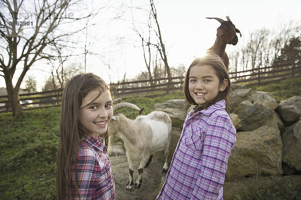 Zwei Kinder  junge Mädchen  im Ziegengehege eines Tierheims.