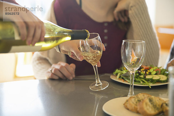 Ein junger Mann und eine junge Frau sitzen zusammen bei einer Mahlzeit und trinken Wein.