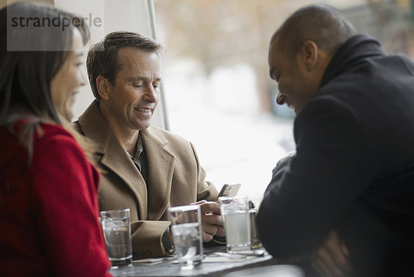 Stadtleben. Eine Gruppe von Menschen  die unterwegs sind  Mobiltelefone benutzen und miteinander sprechen. In einem Café.
