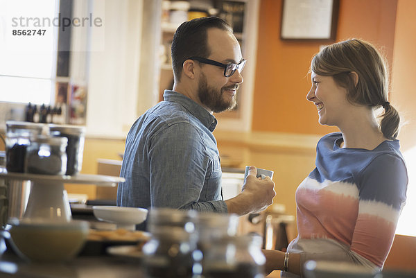Ein Paar sitzt in einem Coffeeshop  lächelt und unterhält sich bei einer Tasse Kaffee.