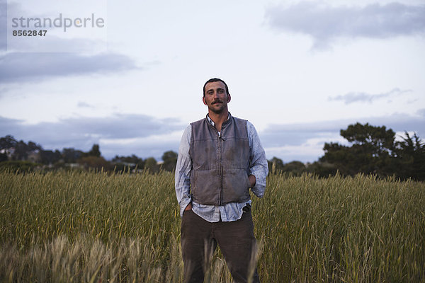 Ein Mann  der an einem Feld mit Getreideanbau steht  beim Sozialfürsorge- und Arbeitsprojekt  dem Obdachlosen-Gartenprojekt in Santa Cruz.