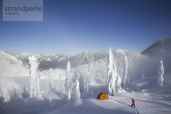Michael Hanson wandert durch tiefen Pulverschnee zu seinem Lagerplatz in den schneebedeckten Cascade Mountains mit Blick auf den Snow Lake.