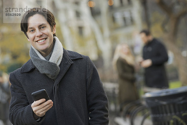 Mann im Stadtpark mit Smartphone
