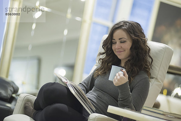 Frau entspannt sich zu Hause beim Lesen mit Kaffee