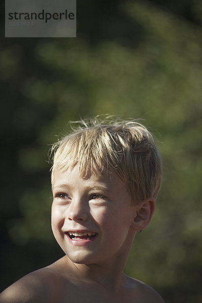 Ein Kind  das seinen Kopf dreht  um über seine Schultern zu schauen  und lächelt.