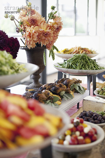 Biologisch zubereitete Salate  Gemüse und Obst auf Gerichten  die für eine Party ausgelegt sind. Ein gedeckter Tisch. Blumen in einer Vase. Ein Essensstand auf einem Bauernhof.