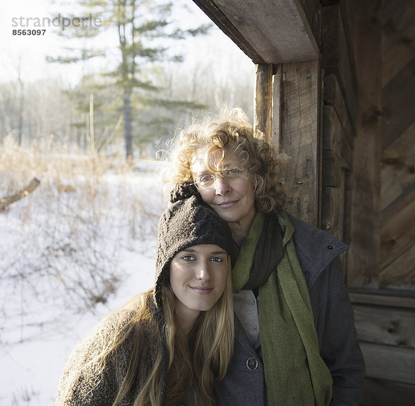 Zwei Menschen  eine Mutter und eine Tochter  Seite an Seite in der Veranda einer Holzscheune auf einem Bauernhof. Ein Wintertag.