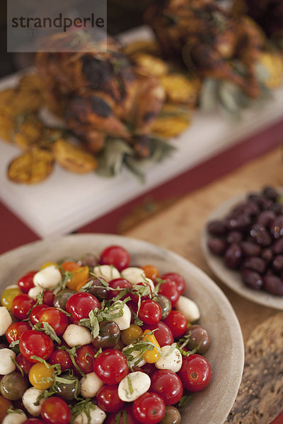 Ein für eine Party gedeckter Buffettisch. Bio-Essen. Salate und ein Hühnergericht.