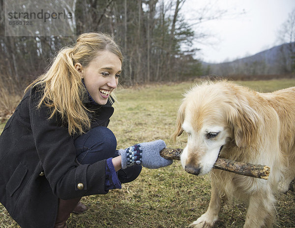 Eine junge Frau  die im Winter mit einem Golden-Retriever-Hund im Freien spazieren geht.