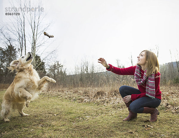 Eine junge Frau  die im Winter mit einem Golden-Retriever-Hund im Freien spazieren geht.