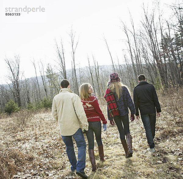 Eine Gruppe von vier Personen  die an einem Wintertag durch den Wald wandert. Zwei Männer und zwei Frauen.